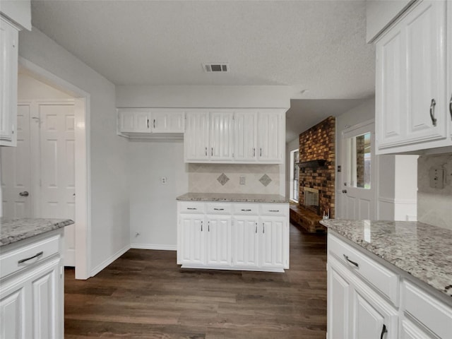 kitchen featuring tasteful backsplash, visible vents, white cabinets, dark wood finished floors, and light stone countertops