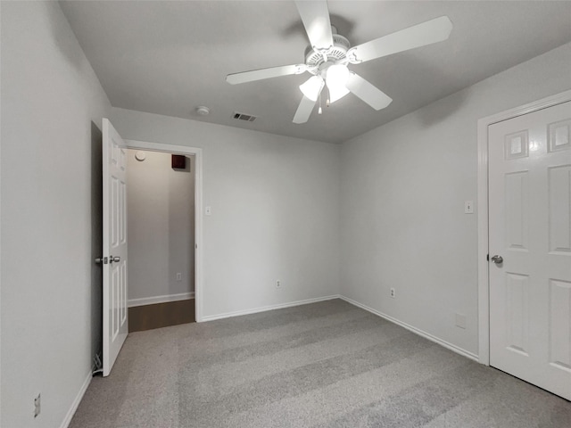 carpeted spare room featuring a ceiling fan, visible vents, and baseboards