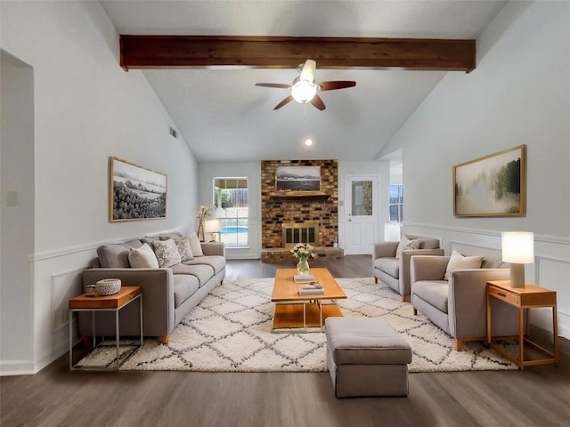 living area with a brick fireplace, beamed ceiling, and wood finished floors