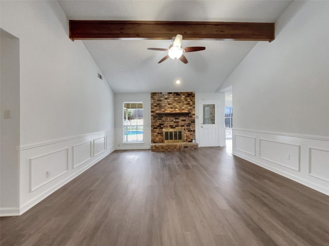 unfurnished living room with lofted ceiling with beams, a brick fireplace, wood finished floors, and a ceiling fan