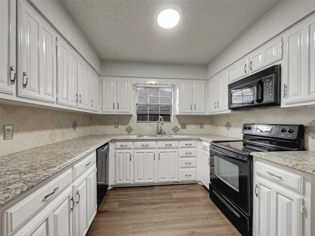 kitchen with black appliances, white cabinetry, dark wood finished floors, and a sink