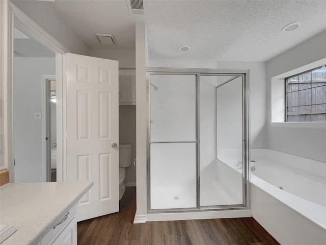 bathroom with visible vents, toilet, wood finished floors, a shower stall, and a bath