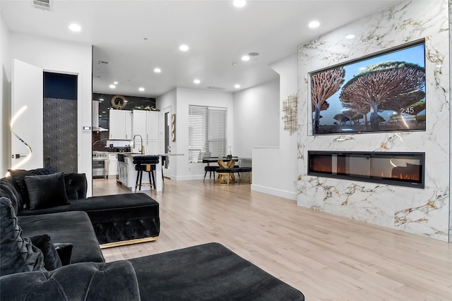 living room featuring visible vents, recessed lighting, light wood-type flooring, and a premium fireplace