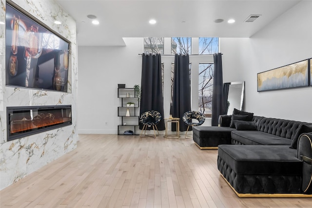 living room featuring a fireplace, recessed lighting, visible vents, light wood-style floors, and baseboards