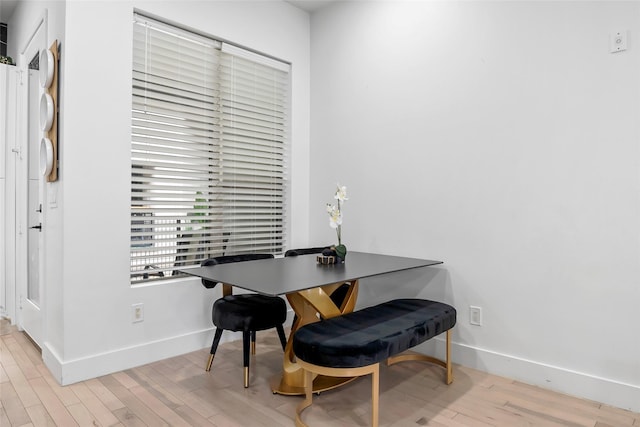 dining space with light wood-type flooring and baseboards