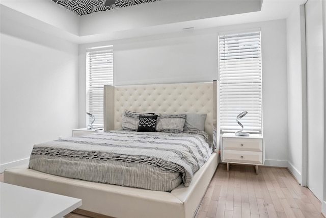 bedroom with light wood-style floors, multiple windows, and baseboards