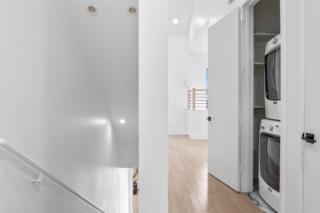 hallway with stacked washer and dryer, light wood-style flooring, and recessed lighting