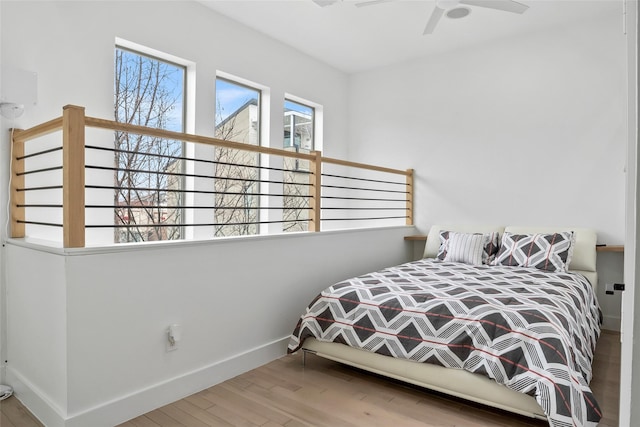 bedroom with a ceiling fan, baseboards, and wood finished floors