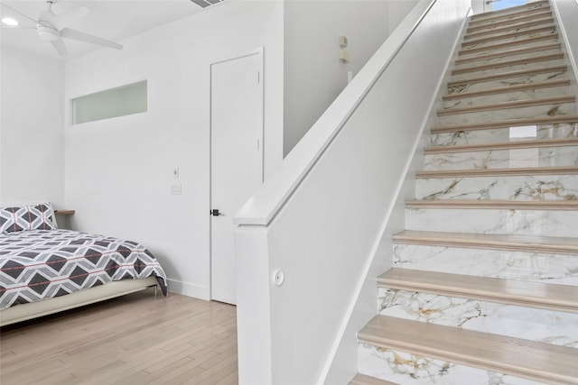 staircase with a ceiling fan and wood finished floors