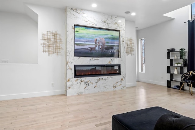 living area featuring baseboards, a fireplace, light wood-style flooring, and recessed lighting