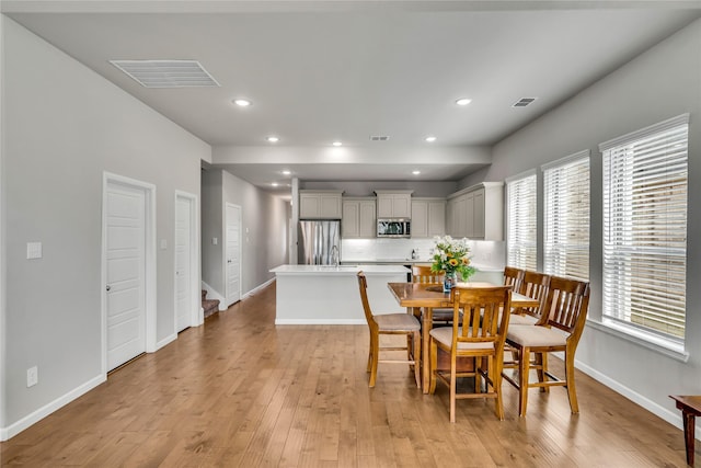 dining area with light wood-style flooring, visible vents, and baseboards