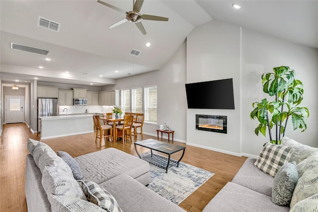 living room with light wood finished floors, ceiling fan, and visible vents