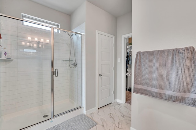 bathroom with a stall shower, marble finish floor, a spacious closet, and baseboards