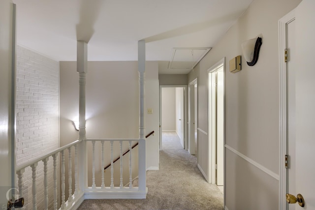 hallway featuring attic access, light colored carpet, and an upstairs landing