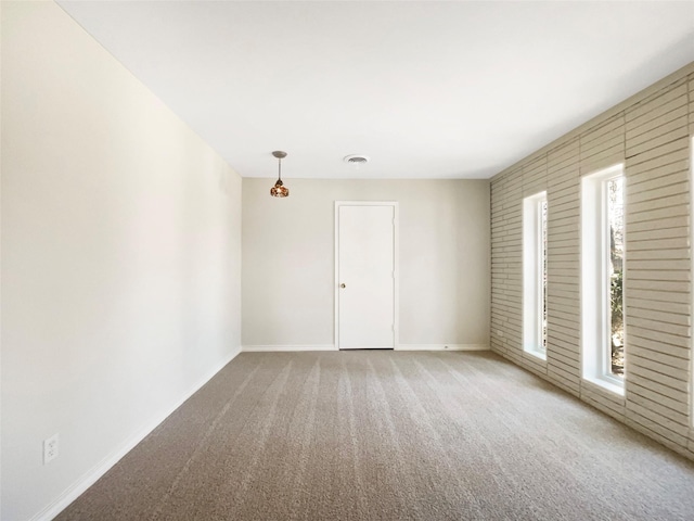 empty room with baseboards, carpet, visible vents, and a healthy amount of sunlight