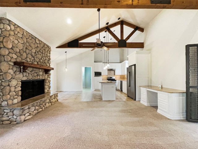 unfurnished living room with ceiling fan, high vaulted ceiling, a stone fireplace, light colored carpet, and beam ceiling