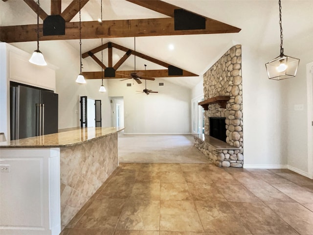 kitchen featuring high end refrigerator, white cabinets, open floor plan, decorative light fixtures, and stone counters