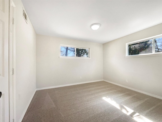 empty room featuring carpet, plenty of natural light, visible vents, and baseboards