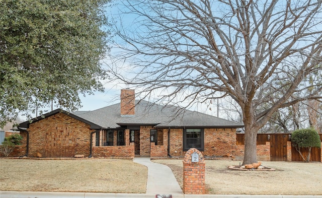 single story home with brick siding, a chimney, a shingled roof, a front yard, and fence