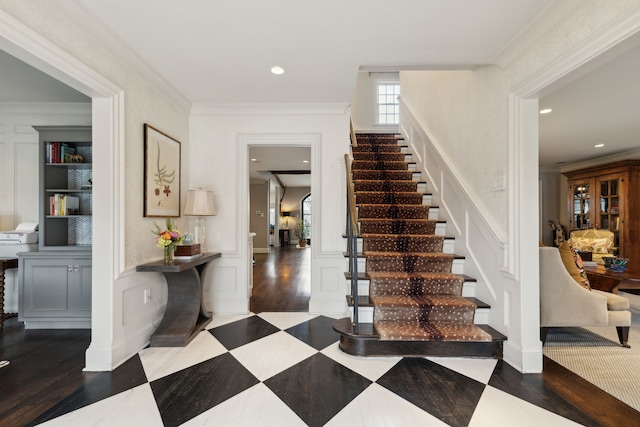 staircase featuring recessed lighting, a decorative wall, crown molding, and wainscoting