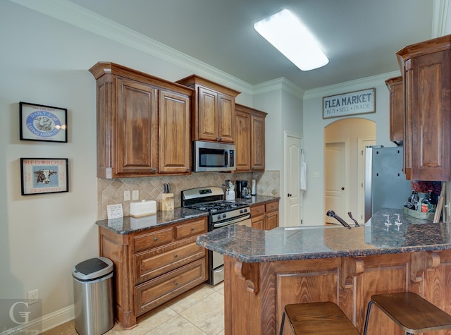 kitchen featuring arched walkways, stainless steel appliances, a peninsula, and a sink