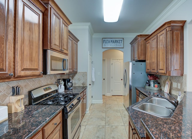 kitchen featuring brown cabinets, arched walkways, stainless steel appliances, and a sink