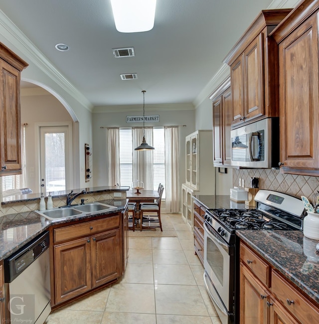 kitchen with visible vents, appliances with stainless steel finishes, brown cabinets, hanging light fixtures, and a sink