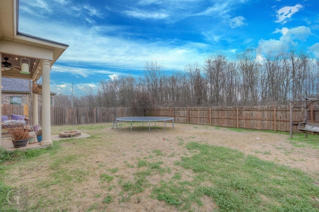 view of yard with an outdoor fire pit, a trampoline, and a fenced backyard