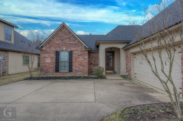 view of front of home with a shingled roof, brick siding, driveway, and an attached garage