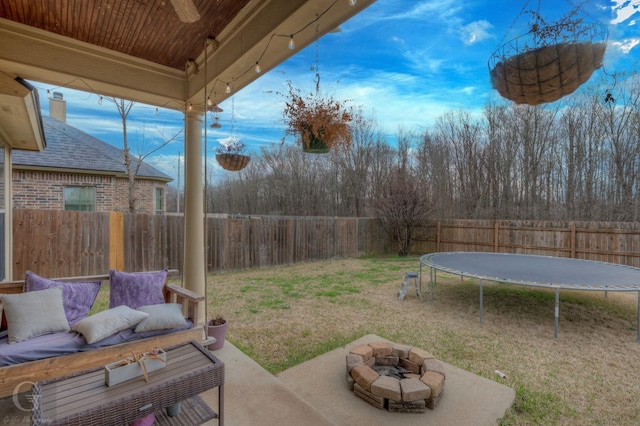 view of yard featuring an outdoor fire pit, a trampoline, a patio area, and a fenced backyard