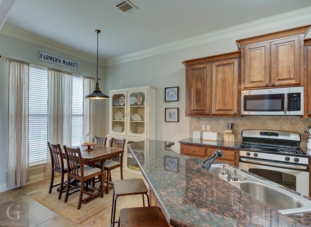 kitchen with a breakfast bar area, stainless steel appliances, visible vents, tasteful backsplash, and pendant lighting