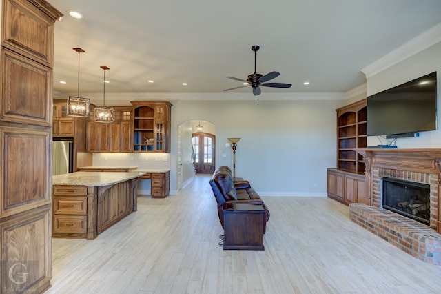 kitchen featuring arched walkways, pendant lighting, brown cabinetry, glass insert cabinets, and open floor plan