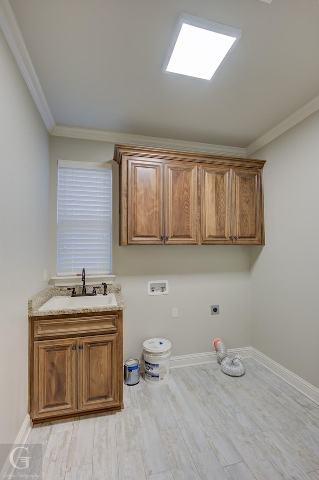 washroom featuring crown molding, hookup for a washing machine, cabinet space, hookup for an electric dryer, and a sink