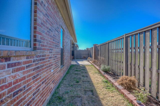 view of side of home featuring brick siding and a fenced backyard