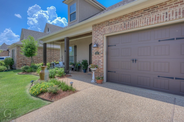 entrance to property featuring brick siding, a yard, covered porch, a garage, and driveway