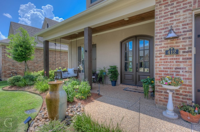 property entrance with a shingled roof, french doors, and brick siding