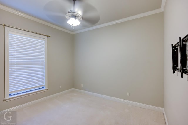 spare room with ceiling fan, baseboards, crown molding, and light colored carpet