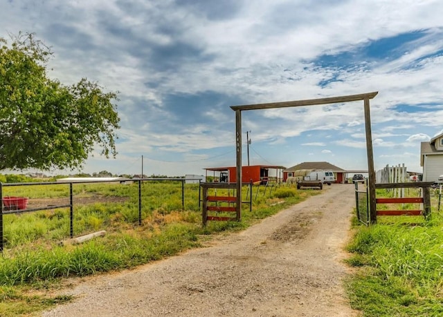 view of road with driveway, a gated entry, and a rural view