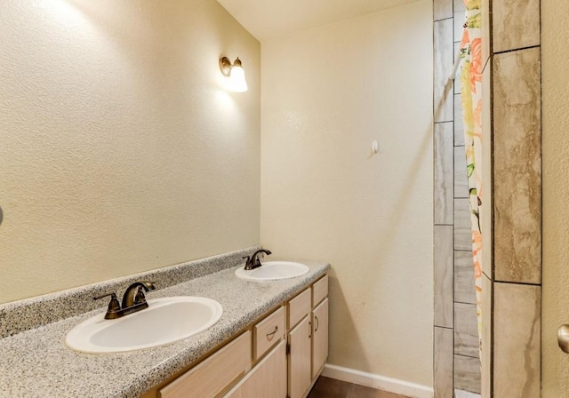 bathroom featuring double vanity, a sink, and baseboards