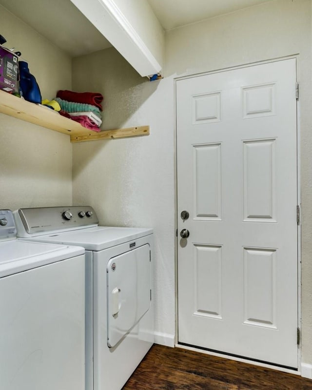 laundry area with laundry area, dark wood-type flooring, washing machine and clothes dryer, and baseboards