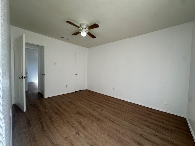 unfurnished bedroom featuring a ceiling fan, dark wood-style flooring, visible vents, and baseboards