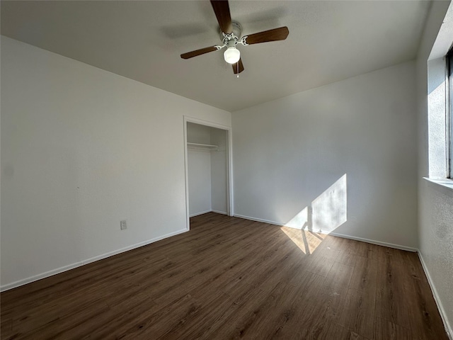 unfurnished bedroom with dark wood-type flooring, a closet, ceiling fan, and baseboards