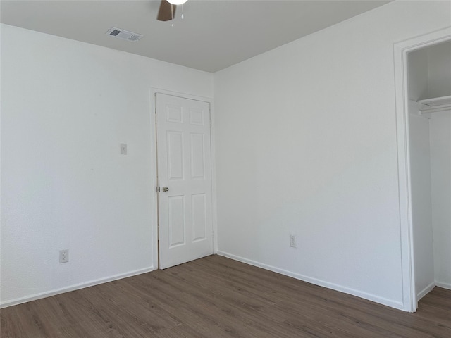 unfurnished bedroom with ceiling fan, dark wood-style flooring, visible vents, baseboards, and a closet