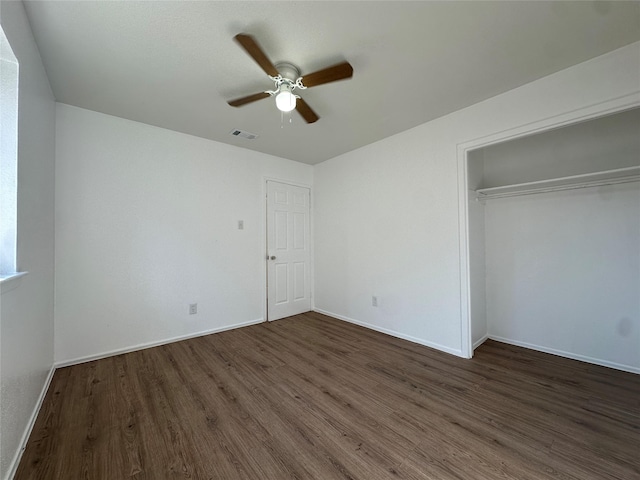 unfurnished bedroom featuring a ceiling fan, visible vents, baseboards, a closet, and dark wood finished floors