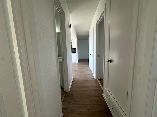 hall with baseboards, dark wood finished floors, and a textured wall