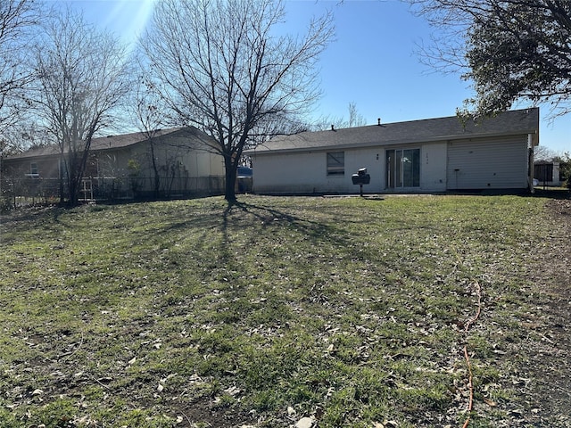 rear view of house featuring a lawn and fence