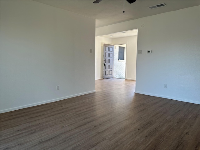 unfurnished room featuring baseboards, dark wood-style flooring, visible vents, and a ceiling fan