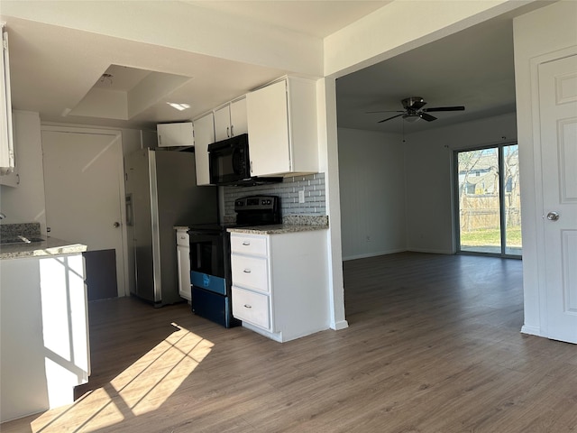 kitchen with wood finished floors, white cabinets, open floor plan, decorative backsplash, and black appliances