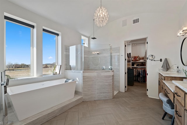 full bathroom featuring visible vents, walk in shower, vanity, a freestanding tub, and a notable chandelier