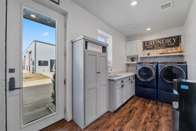 clothes washing area featuring a sink, dark wood finished floors, washing machine and dryer, and visible vents